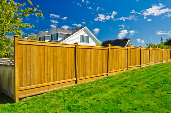 Scène extérieure résidentielle avec clôture en bois neuve installée le long d'une pelouse verte